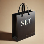 DALL_E_2025-02-19_00.20.55_-_A_stylish_black_shopping_bag_on_a_beige_background._The_bag_is_sleek_modern_and_minimalistic_with_a_premium_look._Bold_capitalized_text_saying_SET_27116822-77f3-4c0c-a29f-3005c0b6e9de.webp